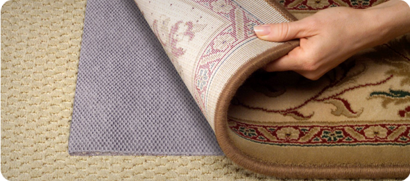 Placing a non-slip pad under an Oriental rug for secure placement.