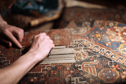 Close-up of hands skillfully performing Oriental rug restoration.
