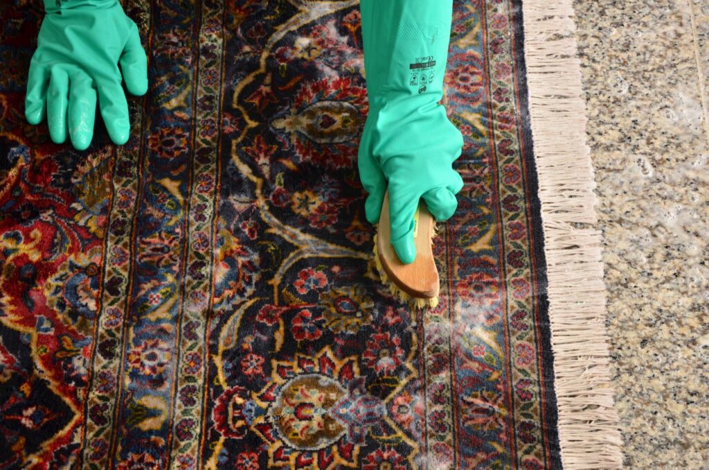 An oriental rug being cleaned with a rug brush for deep cleaning.